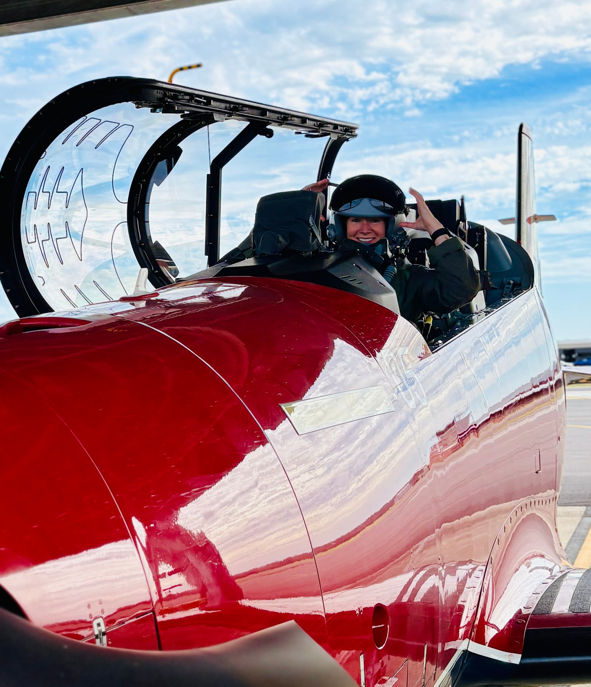 Steffanie in a red aircraft cockpit on the tarmac