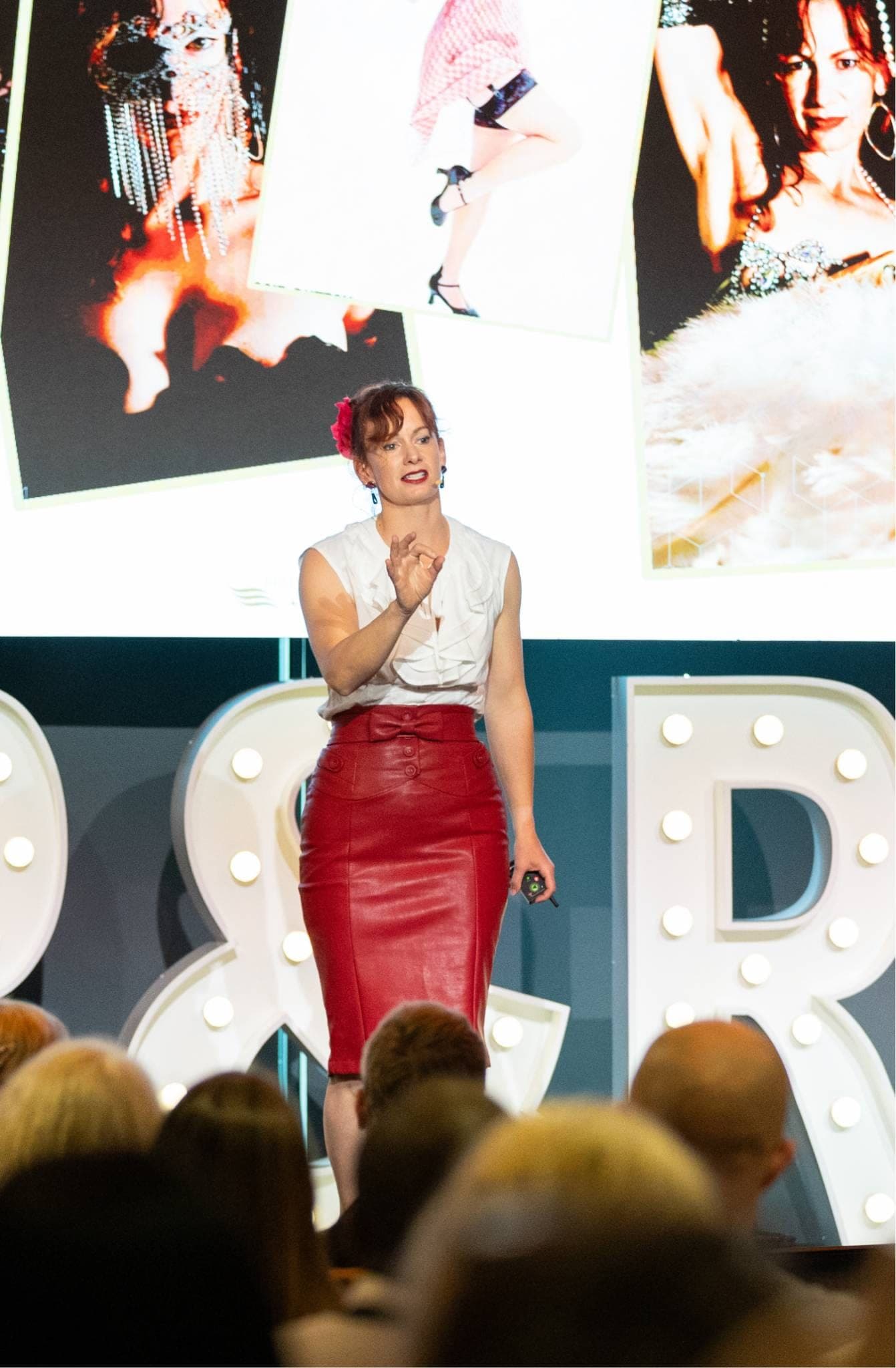 Steffanie Smith delivering a keynote, her performance photographs projected on the screen behind her